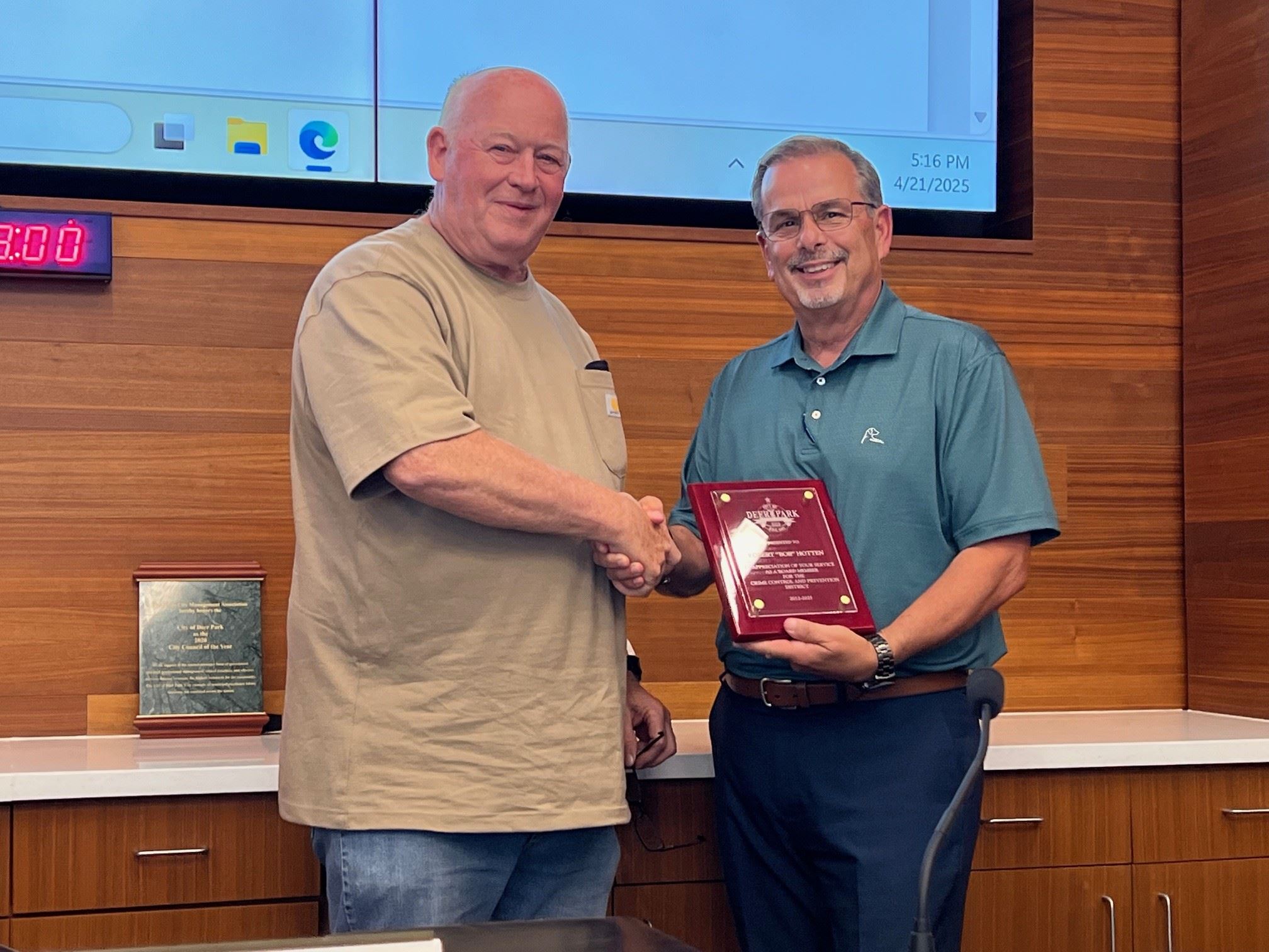 Bob Hotten and Donald Zuckero shaking hands with appreciation plaque