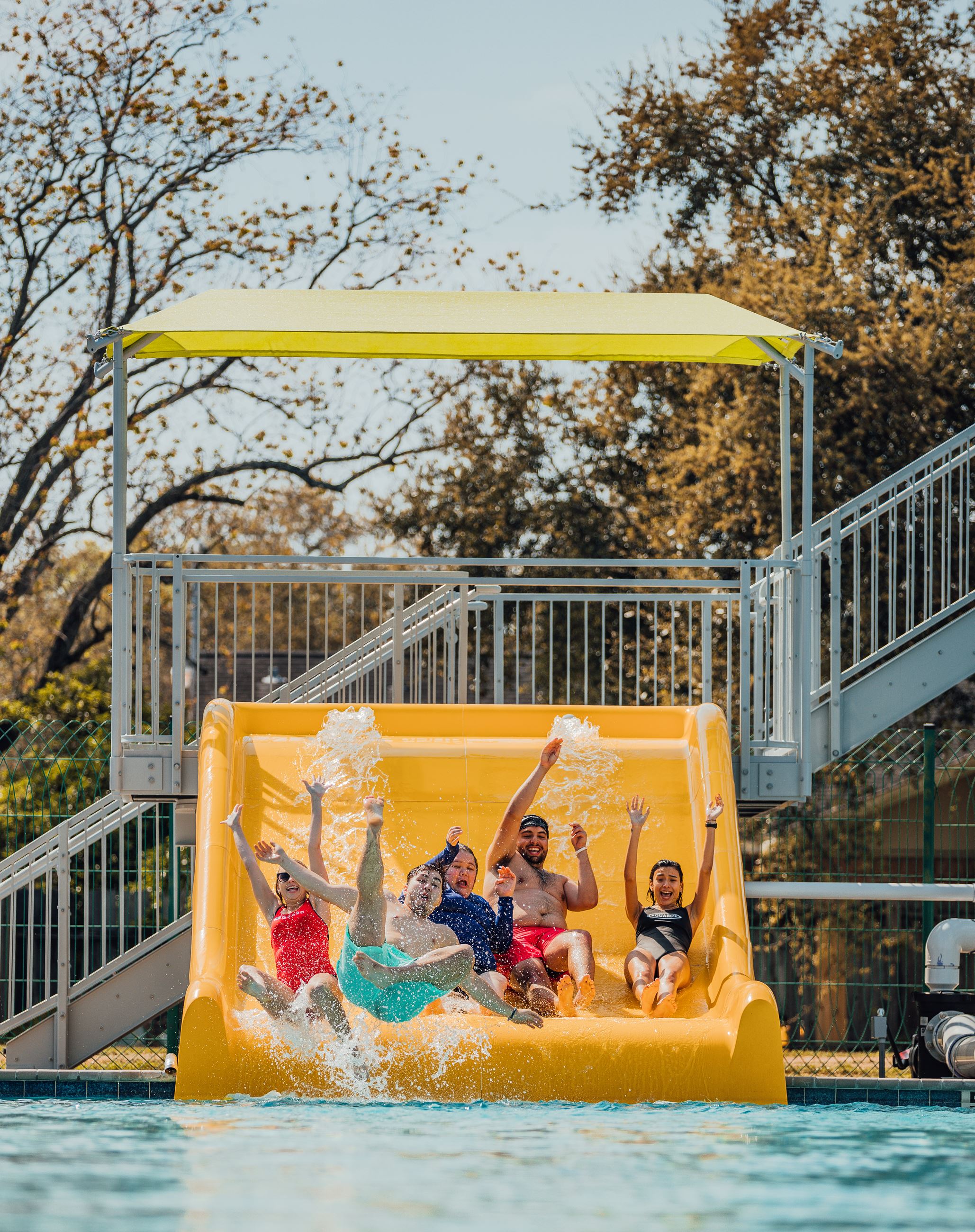 Five people sliding down giant slide into the pool